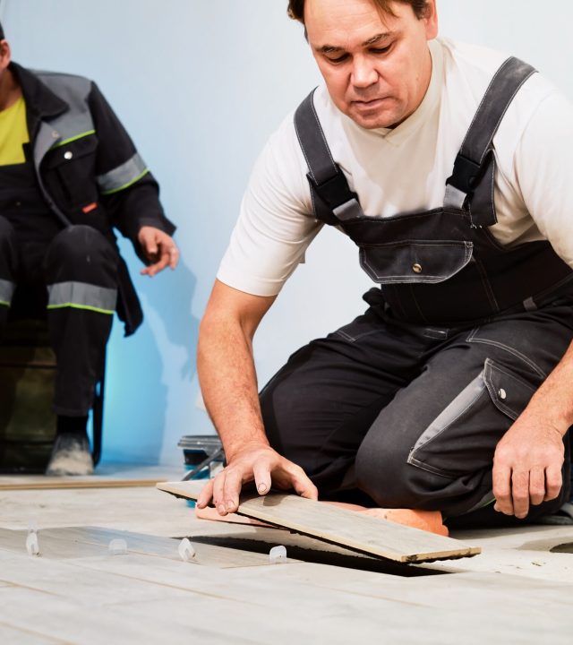 Installing ceramic floor tiles in construction site construction workers. Workers laying tiles on the floor with cement adhesive. Renovating the floor. Installing ceramic floor tiles in construction site construction workers. Workers laying tiles on the floor with cement adhesive. Renovating the floor.